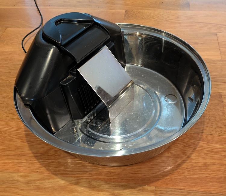 The original fountain: a black plastic pump housing and stainless spillway sitting in a stainless steel bowl.