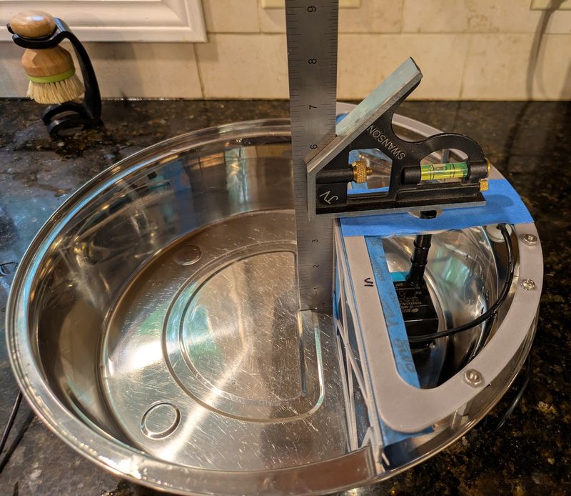 A combination square standing upright in the bowl, measuring the height of the taped-in 3D-printed parts relative to the bowl's rim.